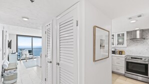 A modern kitchen with white cabinetry, a stainless steel oven, and a view to the outside.
