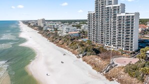 A coastal hotel with multiple floors, a beach view, and a parking area.