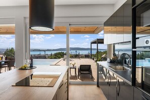 Una cocina moderna con vista al mar, un comedor con mesa y sillas, y un gran ventanal con vistas al océano.