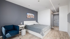 Une chambre à coucher moderne avec un lit, des tables de chevet, une chaise et un tableau au mur.