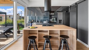 Une cuisine moderne dotée d’un îlot central, de tabourets de bar et offrant une vue sur l’extérieur.