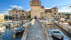 Un bâtiment en pierre doté d’une tour, un sentier en pierre menant à l’eau et plusieurs bateaux amarrés le long du canal.