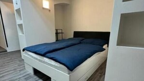 Ein modernes Schlafzimmer mit einem Bett, weißen Wänden und einem grauen Boden.