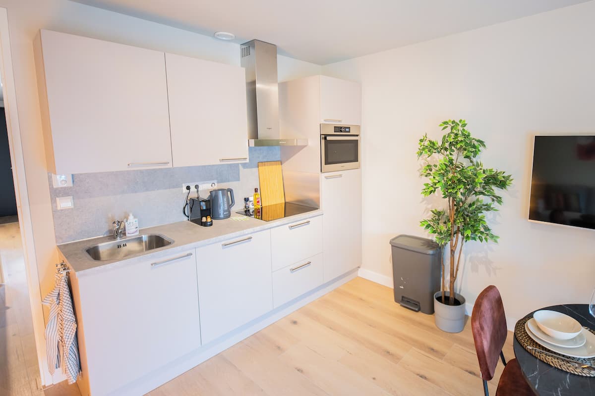 A modern kitchen with white cabinets, stainless steel appliances, and a wooden countertop.