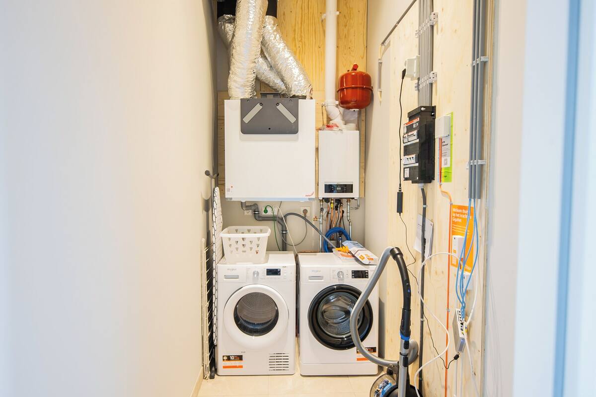 A laundry room with two washing machines, a dryer, and a vacuum cleaner.