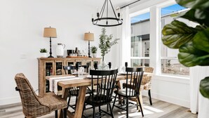 A dining area with a wooden table, black chairs, and a chandelier. - Meridian Marvel Luxury Home (Meridian)