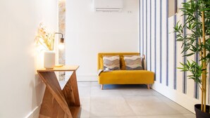 A modern living room with a yellow sofa, a wooden coffee table, and a potted plant. - Bom Retiro's Duplex by LovelyStay (Porto)