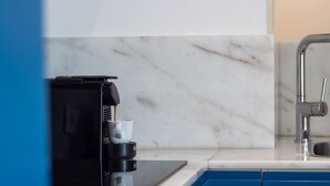 A coffee machine with a cup placed on its drip tray, a modern kitchen sink, and a marble backsplash. - Bom Retiro's Duplex by LovelyStay (Porto)