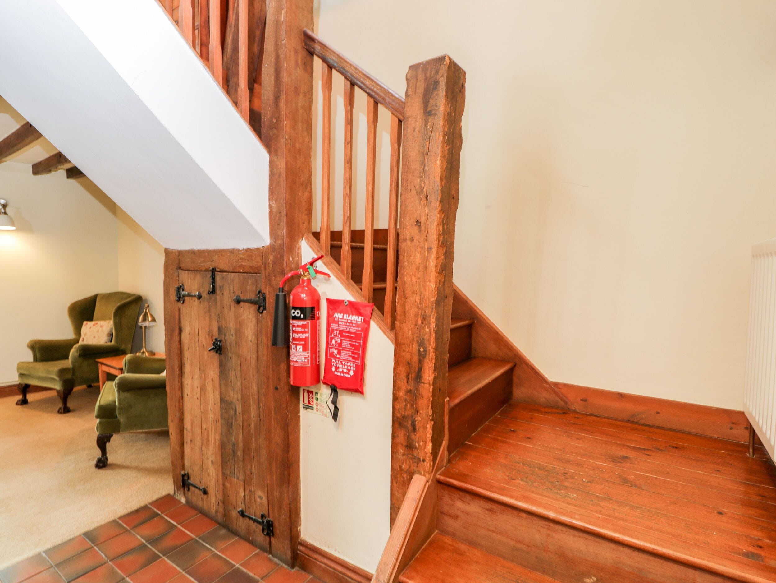 A wooden staircase with a fire blanket and CO2 extinguisher.