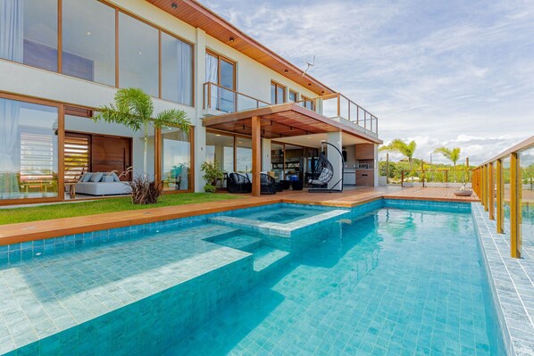 A modern house with a swimming pool, large windows, and outdoor seating.