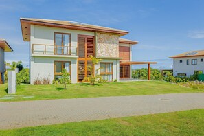 A modern two-story house with a paved driveway, a stone facade, and wooden shutters.