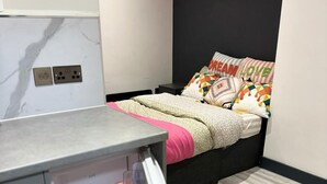Un dormitorio compacto con cama, mesita de noche pequeña y armario empotrado.