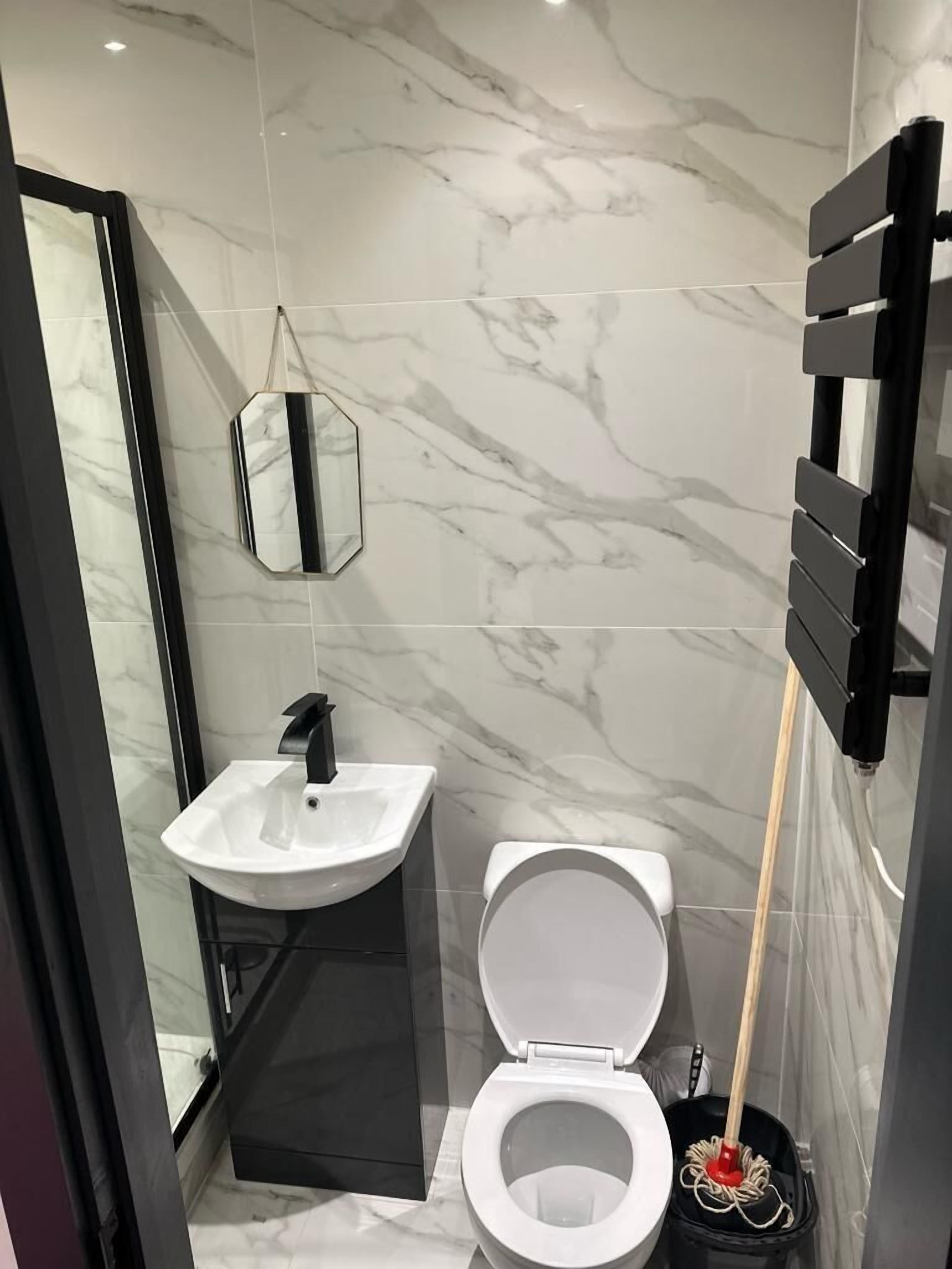 Une salle de bain moderne avec des toilettes blanches, un lavabo noir et un miroir au mur.