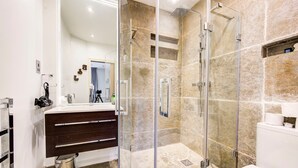 A modern bathroom with a glass-enclosed shower, a vanity with a dark wood finish, and a white toilet. - GuestReady – Stylish 2BR in Angel with Balcony (London)