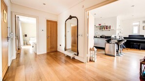 A spacious room with hardwood flooring, a large mirror, and a modern kitchen with a dining area. - GuestReady – Stylish 2BR in Angel with Balcony (London)