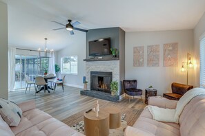 A spacious living room with a fireplace, comfortable seating, and a dining area with natural light. - Fully Remodeled St Petersburg Home w/ Private Pool (St. Petersburg)