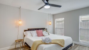 A bedroom with a bed, bedside lamps, a ceiling fan, and a window with blinds. - Fully Remodeled St Petersburg Home w/ Private Pool (St. Petersburg)