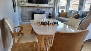 Un área de comedor con una mesa y sillas de madera, una chimenea y un sofá al fondo.