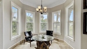 A dining area with a round glass table, four chairs, and a chandelier. - Family fun by the beach! 5500 sq ft with 5 BRs, 5 baths, game room, heated pool (Destin)