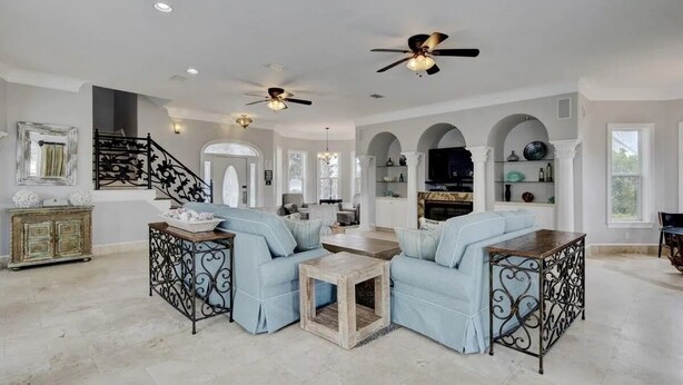 A spacious living room with a high ceiling, two light blue sofas, a wooden coffee table, and a fireplace. - Family fun by the beach! 5500 sq ft with 5 BRs, 5 baths, game room, heated pool (Destin)