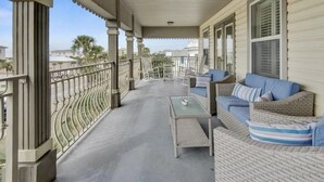 A covered porch with wicker furniture, a table, and a railing. - Family fun by the beach! 5500 sq ft with 5 BRs, 5 baths, game room, heated pool (Destin)