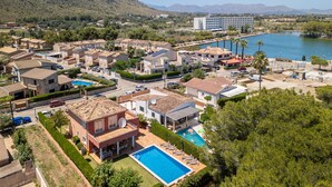 A residential area with houses, a swimming pool, and a large body of water in the background. - House Massanet for 8 with swimming pool near the beach and all amenities (Puerto de Alcudia)