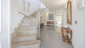 A spacious hallway with a marble staircase, a wooden bench, and a console table. - House Massanet for 8 with swimming pool near the beach and all amenities (Puerto de Alcudia)