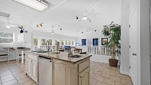 Una cocina amplia con una isla grande, muebles blancos y un comedor con vistas.