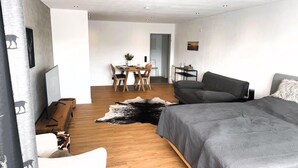 Ein modernes Schlafzimmer mit einem großen Bett, einer Couch, einer Essecke mit Tisch und Stühlen sowie einem kleinen Nachttisch mit Lampe.