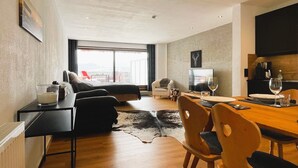 Ein modernes Hotelzimmer mit einem großen Bett, einem Schreibtisch, einem Essbereich und einem Fernseher.