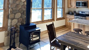 Eine rustikale Küche mit Steinwand, Holzbalkendecke und einem großen Chandelier aus Geweihen.