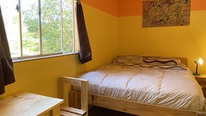 A room with a wooden bed, a desk, and a window with curtains. - Willhouse Hostel (Pucón)