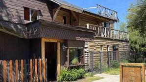 A rustic wooden building with a balcony, a wooden fence, and a sign indicating it is a hostel. - Willhouse Hostel (Pucón)