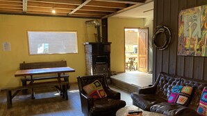 A cozy living room with a fireplace, leather sofas, a wooden bench, and a colorful rug. - Willhouse Hostel (Pucón)