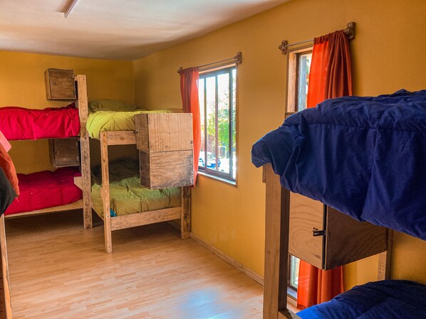 A dormitory room with bunk beds, wooden cabinets, and windows with curtains. - Willhouse Hostel (Pucón)