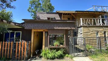 A rustic cabin with a wooden exterior, a balcony, and a fenced yard.