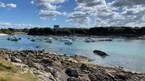 A rocky shoreline with boats docked in calm waters. - Maison à Cleder sur la Cote des Sables (Cléder)