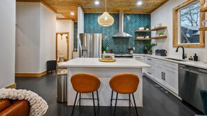 A modern kitchen with a central island, stainless steel appliances, and a herringbone-patterned backsplash. - Private Pond | Kayaks · Spa Bath | Romantic Cabin (Broken Bow)