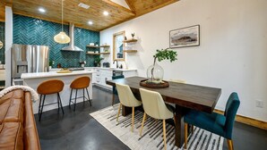 A modern kitchen with a herringbone tile backsplash, wooden ceiling beams, and a dining area with a wooden table and four chairs. - Private Pond | Kayaks · Spa Bath | Romantic Cabin (Broken Bow)