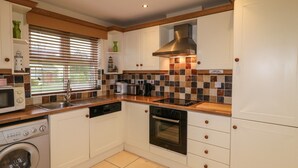 Une cuisine avec des meubles blancs, un lave-vaisselle, un lave-linge, une cuisinière et un four à micro-ondes.