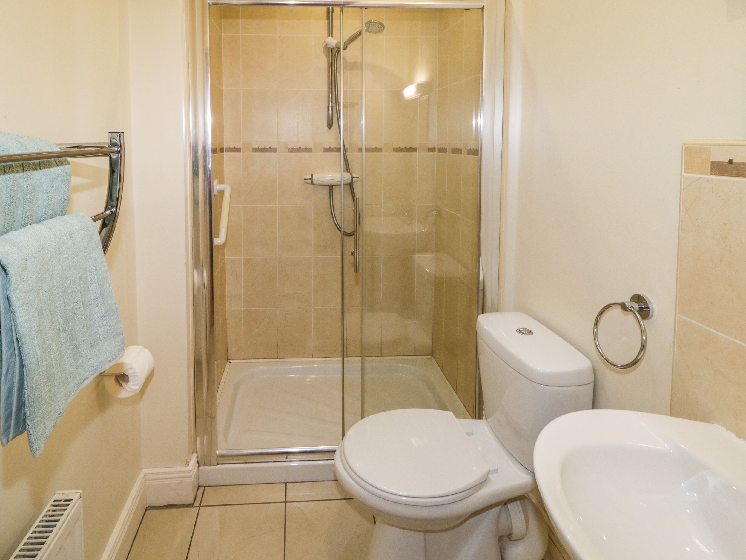 A bathroom with a glass-enclosed shower, a toilet, and a sink.