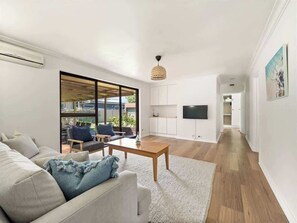 A modern living room with a sofa, coffee table, and a TV mounted on the wall. - Bluewater Retreat - Pet-Friendly Coastal Oasis (Broadwater)