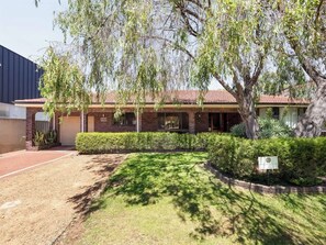 A two-story building with a brick facade, a covered patio, and a well-maintained lawn.