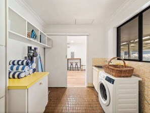 A laundry room with a washing machine, a yellow counter, and a window.