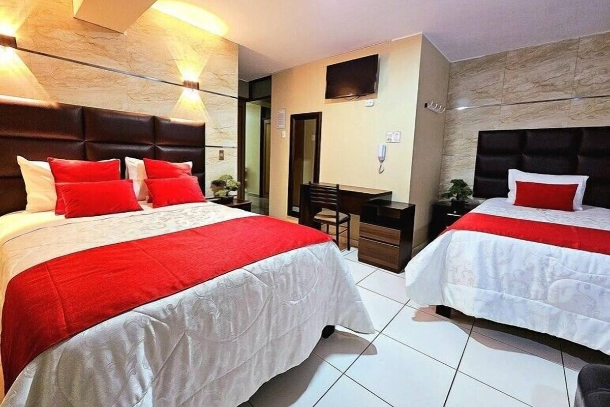 A hotel room with two beds, a desk, and a TV.
