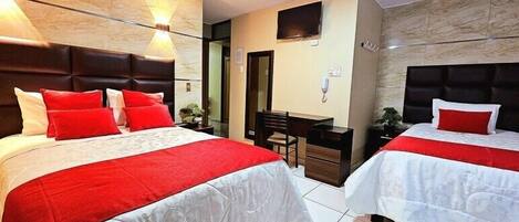 Habitación de hotel con dos camas, un escritorio y un televisor.