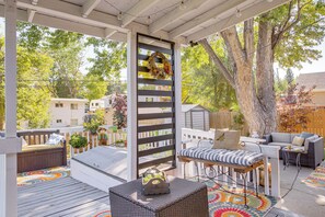 A covered outdoor patio with a wooden deck, a seating area with a sofa and a table, and a decorative wreath on the wall. - 4 Mi to Hwy Access for Mtn Fun: Family Getaway! (Lakewood)