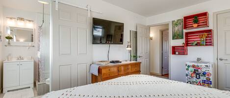 Un dormitorio con una cama grande, un aparador, un televisor y un refrigerador.