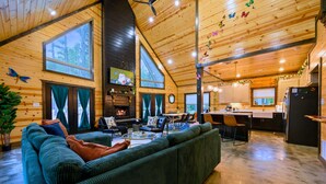 A spacious living area with a large sofa, a fireplace, and a dining area with a kitchen in the background.