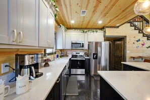 Une cuisine moderne avec des armoires blanches, des appareils en acier inoxydable et un plafond en bois.